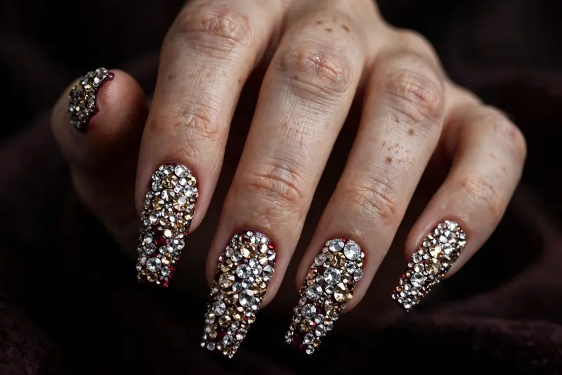 Full-coverage crystal coffin bedazzled nails in deep burgundy with champagne crystals