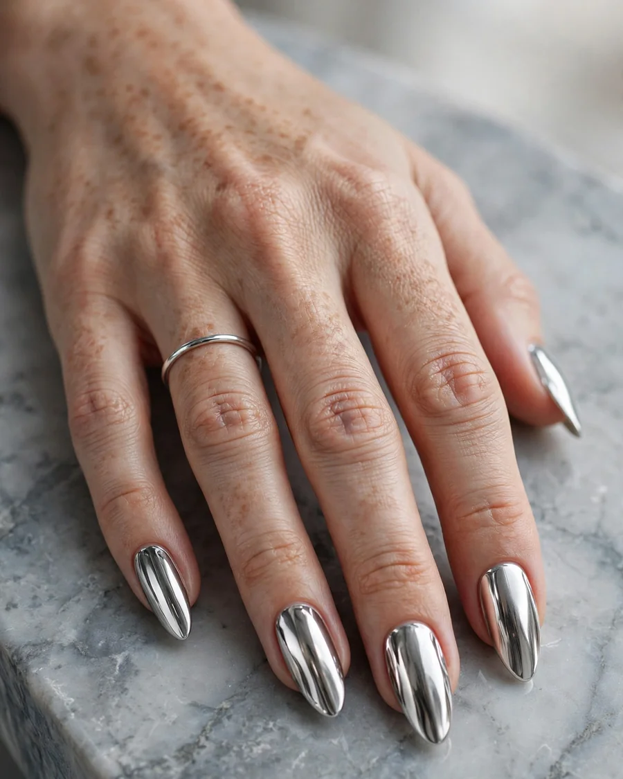 Molten silver mirror chrome nails with liquid platinum finish on long almond nails for fall 2026