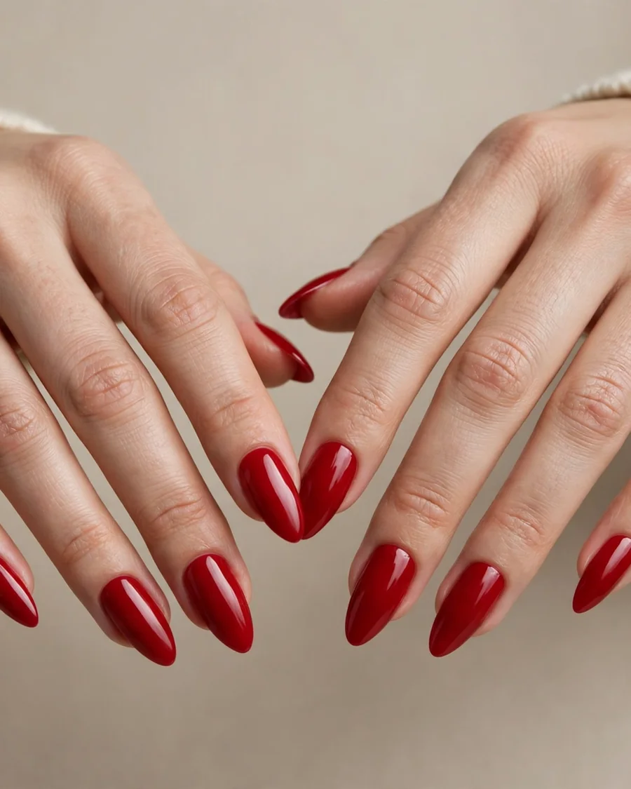 Classic cherry red almond nails with glossy polish, cream knit sweater, editorial beauty photography